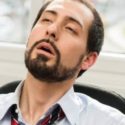 Man appearing fatigued in an office setting, illustrating the importance of air conditioning maintenance during summer heat.
