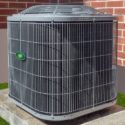 Air conditioning unit on concrete slab next to brick wall, showcasing reliable HVAC functionality for summer comfort.