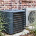 Gray air conditioning units outdoors with green grass, showcasing Chad's HVAC solutions.