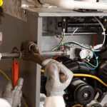 Technician servicing HVAC machinery with tools, emphasizing maintenance skills at Chad's AC Direct in Montgomery, Alabama.