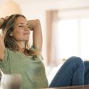 Relaxed woman in a green shirt leaning back in a bright space, highlighting comfort for HVAC service awareness.
