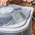 Technician servicing an air conditioning unit with tools, highlighting HVAC maintenance for Chad's AC Direct.