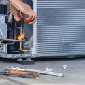 Technician repairing appliance outdoors, with tools nearby and sparks visible, related to Chad's AC Direct HVAC services.