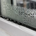Raindrops on a window frame, highlighting condensation above a window sill at Chad's HVAC services location.