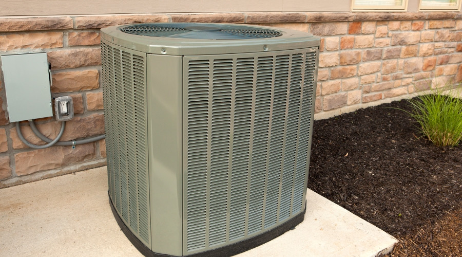 Air conditioning unit installed outside a residential building, highlighting efficiency concerns and maintenance needs related to HVAC systems.